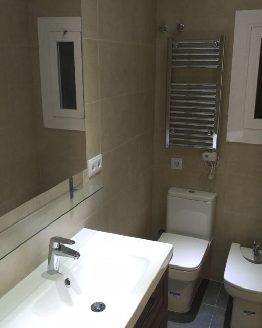 Baño reformado con plato de ducha y toallero eléctrico