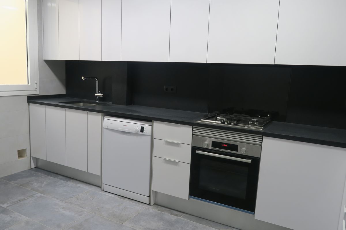 Cocina reformada con muebles blancos y encimera negra