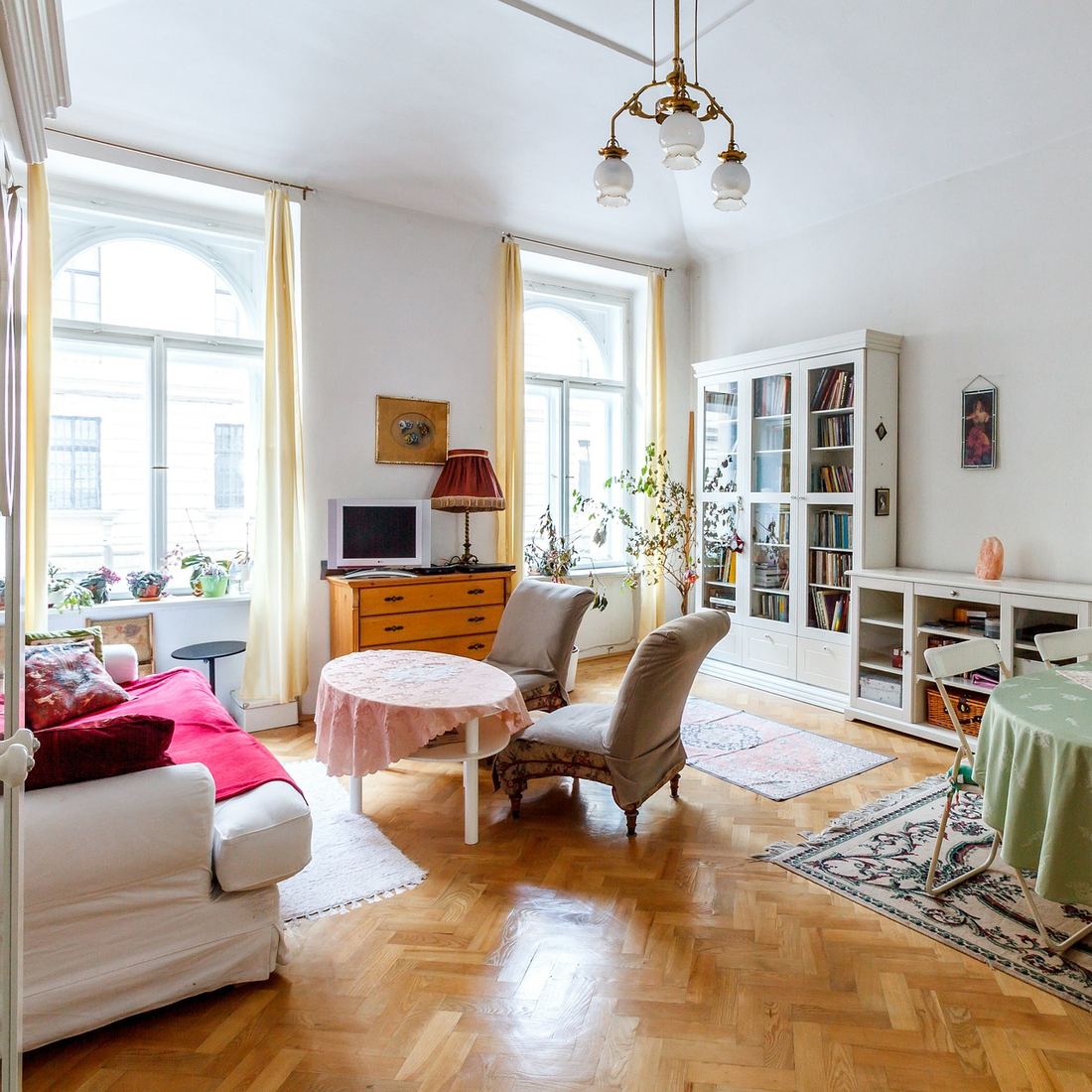Salón luminoso con suelo de parquet, grandes ventanales y librerías blancas